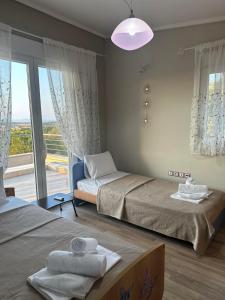 a bedroom with two beds and a large window at Sunrise Villa in Kassandria