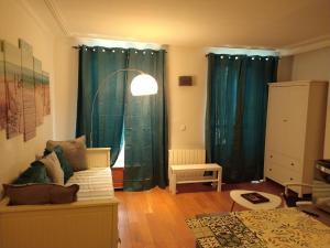 a living room with green curtains and a couch at Studio Pont de Sèvres bien situé in Sèvres