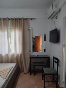 a room with a couch and a desk and a television at Villa Janilla in Dhërmi