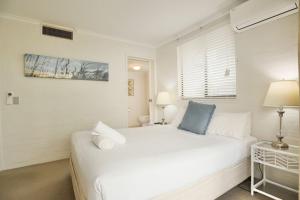 a white bedroom with a white bed and a window at Beach Lovers Dream 2BR in Noosa Heads +26 photos