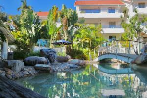 a swimming pool with a bridge and a building at Beach Lovers Dream 2BR in Noosa Heads
