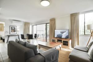 a living room with a couch and a television at Beach Lovers Dream 2BR in Noosa Heads