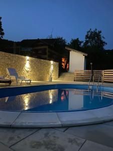 a swimming pool at night with a stone wall at Vidovo Domacinstvo in Banja Luka