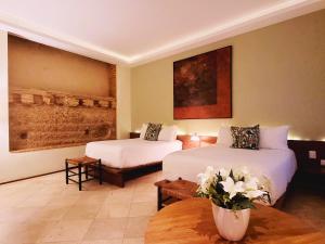a hotel room with two beds and a vase of flowers at LUCA HOTEL Heritage Residences Signature Collection in Santo Domingo