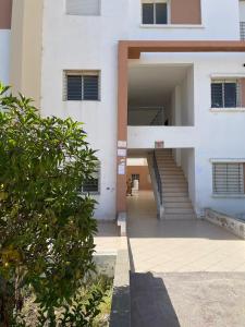 Bel appartement a tanger beach في طنجة: مبنى أبيض مع درج يؤدي إلى باب