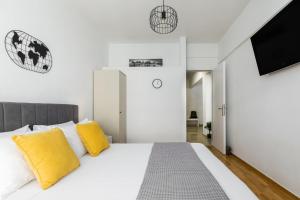 ein Schlafzimmer mit einem weißen Bett und gelben Kissen in der Unterkunft 53 Central Luxury Apartment Kalamaria Thessaloniki in Thessaloniki