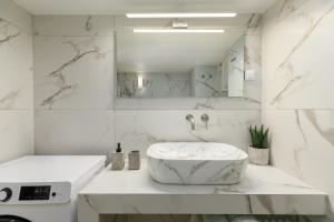 ein weißes Badezimmer mit Waschbecken und Spiegel in der Unterkunft 53 Central Luxury Apartment Kalamaria Thessaloniki in Thessaloniki + 16 Fotos