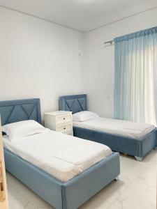 Valbona Apartment في سارنده: سريران زرقان في غرفة مع نافذة