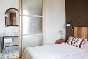 a bedroom with a bed and a sink and a mirror at Artesa Suites & Spa in Santo Tomé del Puerto