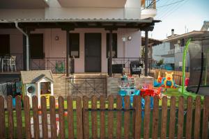 a wooden fence in front of a house with a playground at Emily Apartment 5 in Chrysoupolis