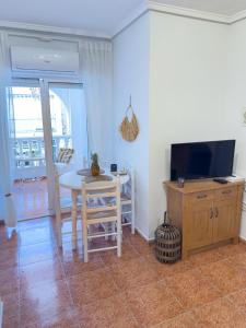 un salon avec une table et une télévision dans l'établissement Torrevieja Seaside Escape, à Torrevieja