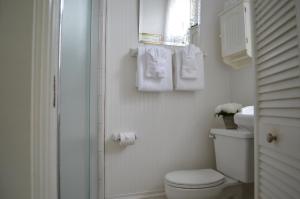 a white bathroom with a toilet and a window at Old Powder House Inn in Saint Augustine