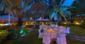 a group of tables with white chairs and palm trees at Royal Orchid Resort & Convention Centre, Yelahanka Bangalore in Bengaluru