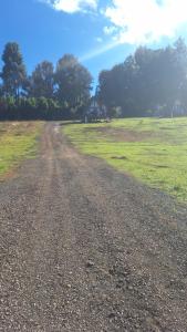 a dirt road leading to a field with a house at CABAÑAS KEIKARY campig in Valle de Bravo