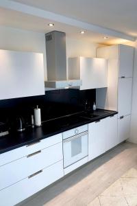 a kitchen with white cabinets and black counter tops at Apartment Antinous Split in Split +13 photos