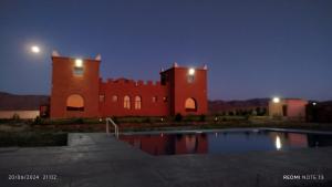 a large red building with a pool in front of it at DAR AL QANASS IMANE in Midelt