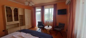 a bedroom with a bed and two chairs and a window at Arnika Vendégház in Hajdúszoboszló