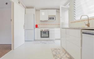 Una cocina blanca con gabinetes y electrodomésticos blancos. en Beach Front Apartment, en Sant Vicenç de Montalt 12 fotos más
