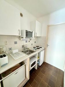 una cucina con mobili bianchi e un lavandino di A 20min d AJACCIO, Grand studio 3 personnes - pieds dans l'eau - accès direct plage - vue mer exceptionnelle a Casaglione