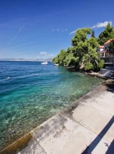 a body of water with trees and a boat in the water at Apartment Karla in Splitska