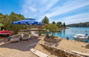 a beach with chairs and an umbrella and a boat at Beautiful Apartment In Punta Kriza in Punta Križa