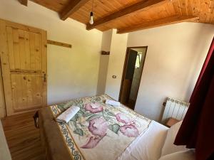 a bedroom with a bed with a floral bedspread at Guest house prek bjeshka in Theth