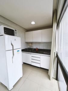 Una cocina con gabinetes blancos y un refrigerador blanco. en 1138 Flat Triplo Garvey - Esplanada e Congresso, en Brasilia