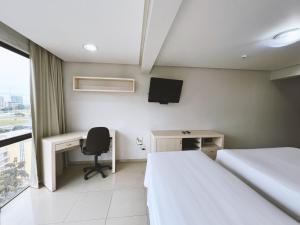 Una habitación de hotel con dos camas, un escritorio y un televisor. en 1138 Flat Triplo Garvey - Esplanada e Congresso, en Brasilia 3 fotos más