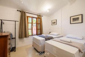 a bedroom with two beds and a window at Casa Charmosa c/ Churrasq/ na Vila Planalto ACT029 in Brasilia