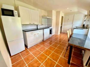 a kitchen with white cabinets and a red tile floor at Carefree Cottage in Marstow +14 photos