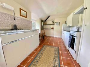 a kitchen with white appliances and a brown tile floor at Carefree Cottage in Marstow