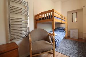 a bedroom with a bunk bed and a chair at Carefree Cottage in Marstow