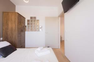 a bedroom with a white bed and a wooden cabinet at Malvina Homes Knossou in Áno Fortétsa