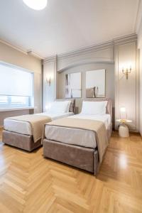 two beds in a large room with wood floors at Urban Elegance in Kolonaki in Athens