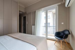 a bedroom with a bed and a chair next to a window at Urban Elegance in Kolonaki in Athens