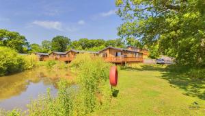 a house with a pond in front of it at Poppy An Immaculate Lake side Lodge the Perfect Retreat, Sleeps 4 in Ryde