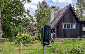 a black house with a wind meter in front of it at Amazing Home In Lidhult With Wifi in Bassarås