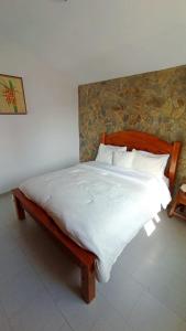 un letto con lenzuola e cuscini bianchi in una camera da letto di Con Vista al Mar y Terraza Privada, Céntrico a Tucacas