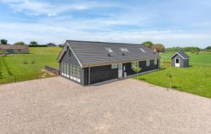 a black house on a gravel driveway in a field at Four-Bedroom Holiday Home In Bagenkop in Bagenkop