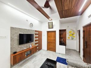 Una sala de estar con un televisor en la pared. en Ganga Homes by Alchemy Homes, Ayyanthole, Thrissur, en Trichūr