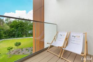 a balcony with a chair and a large window at Apartament Prestige 224 - tuż przy plaży -BASEN, sauna, jacuzzi w cenie pobytu - Easy - Rent Apartments in Pobierowo