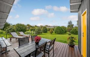 a wooden deck with chairs and a table with flowers at Amazing Home In Allingåbro With Wifi in Allingåbro +12 photos