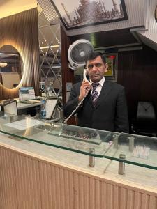 a man in a suit talking on a cell phone at HOTEL TOURIST INN in Lahore