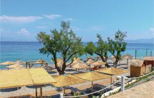 a beach with many straw umbrellas and the ocean at Awesome Apartment In Melissi Korinthia in Dhiminión