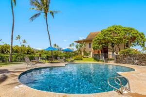 a pool with chairs and palm trees and a house at Makanui 711 - Mountain View in Kipu