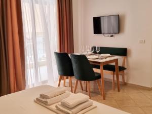 a dining room with a table and chairs and a tv at Arte Apartment in Sarandë