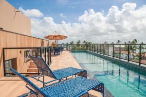 a swimming pool with two chairs and an umbrella at Melhor localização Porto Galinhas 50M DO MAR E CENTRINHO - COM E SEM PISCINA PRIVATIVA Family Flats Porto de Galinhas in Porto De Galinhas +62 photos