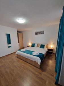 a bedroom with a large bed and blue curtains at Casa Emil in Blaja