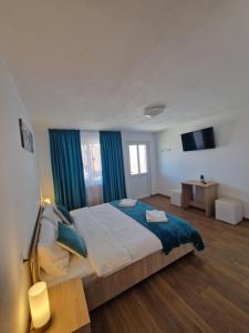 a bedroom with a large bed with blue curtains at Casa Emil in Blaja