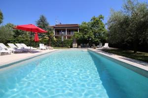 a swimming pool with a red umbrella and chairs and a house at Bungalow Lavanda mit Pool und Garten in Porec in Poreč